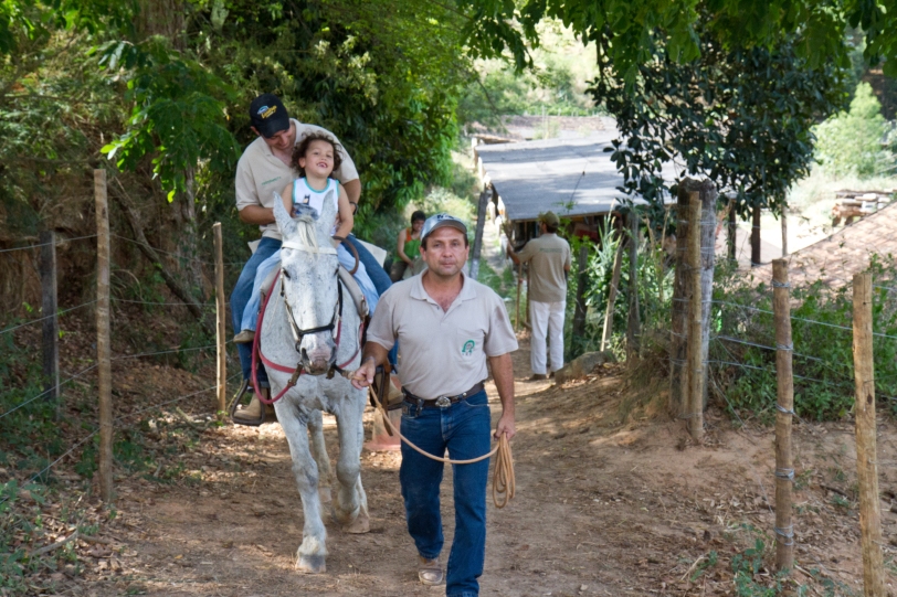 Cebolinha,  presidente da associação, conduz o cavalo de um praticante, enquanto Leonardo, o psicólogo, acompanha outro praticante (detalhe ao fundo) 